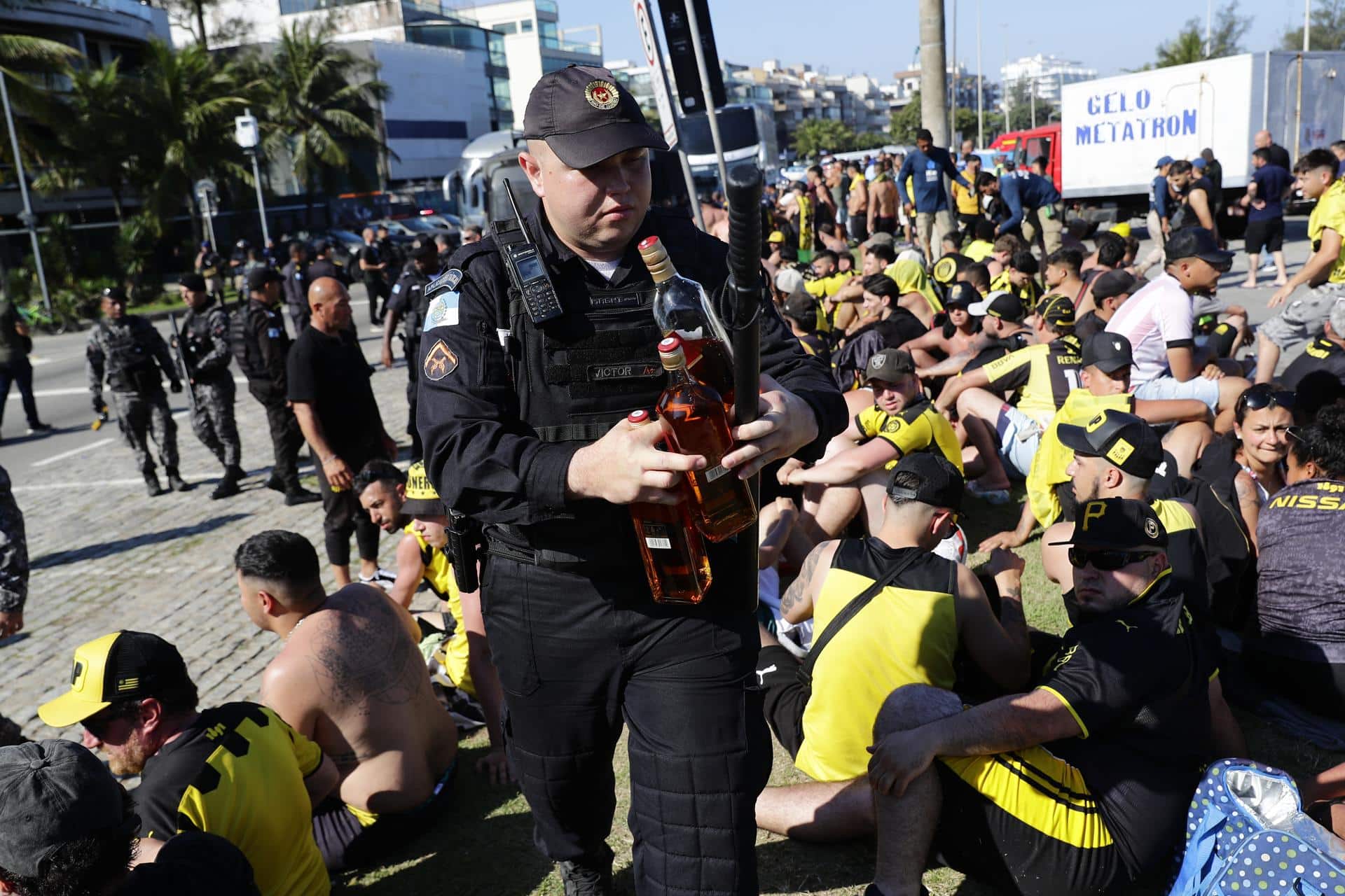 Un integrante de la policía incauta botellas con licor a los fanáticos del Peñarol de Uruguay, luego de ser detenidos en la playa de Pontal en Río de Janeiro. EFE/ André Coelho