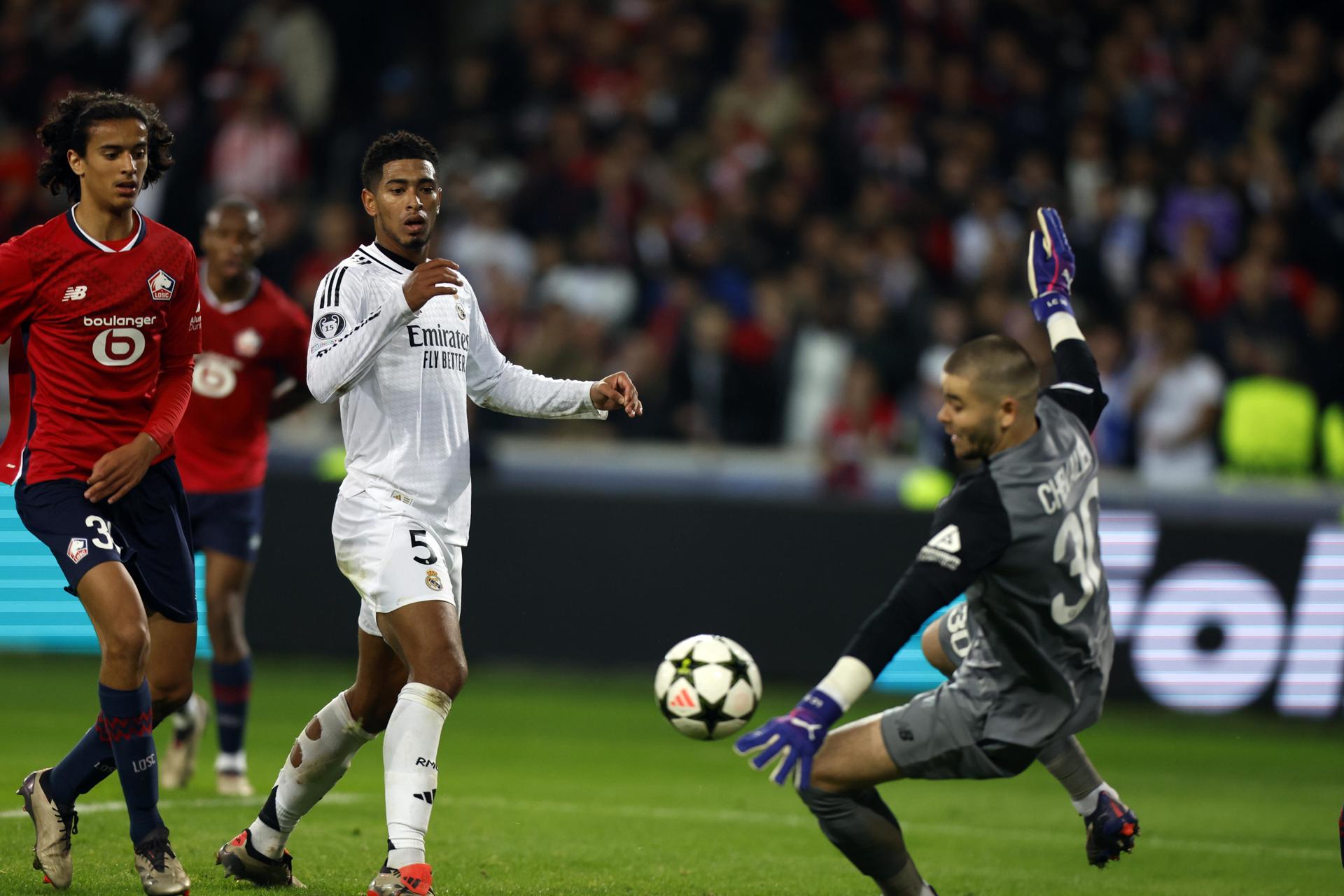 El portero francés del Lille Lucas Chevalier (d) realiza una parada a disparo del inglés del Real Madrid Jude Bellingham (i). EFE/EPA/MOHAMMED BADRA