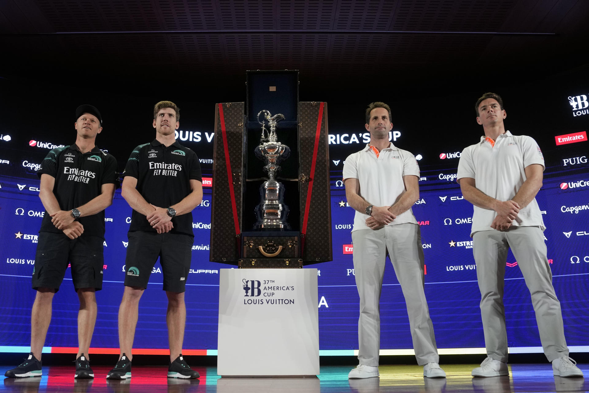 Los timoneles del equipo defensor Team New Zealand, Peter Burling (2i) y Nathan Outteridge (i), y del equipo desafiante INEOS Britannia, Ben Ainslie (2d) y Dylan Fletcher (d), posan ante la Copa de las cien guineas, durante la rueda de prensa de presentación de la Copa del América 2024 que mañana comenzará a disputarse en las aguas de Barcelona. EFE/Enric Fontcuberta