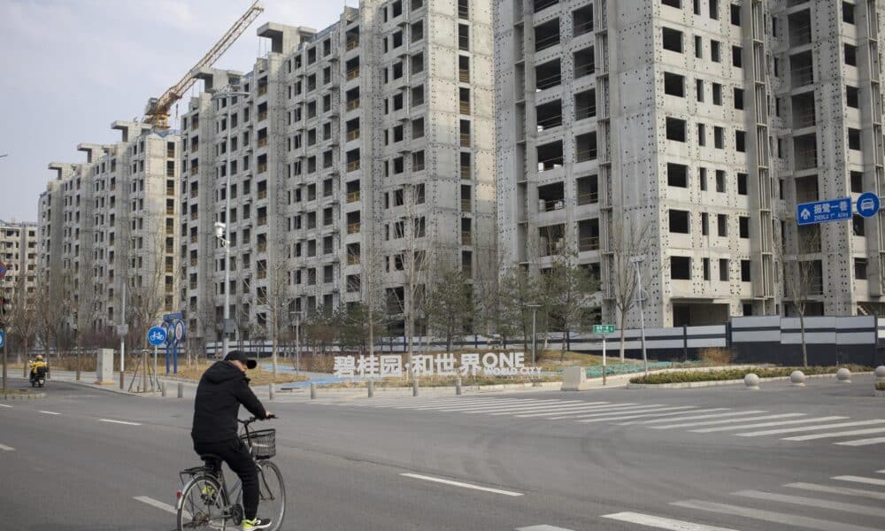 Fotografía de archivo de un hombre en bicicleta junto a un sitio de construcción en Pekín, China. EFE/ANDRÉS MARTÍNEZ CASARES