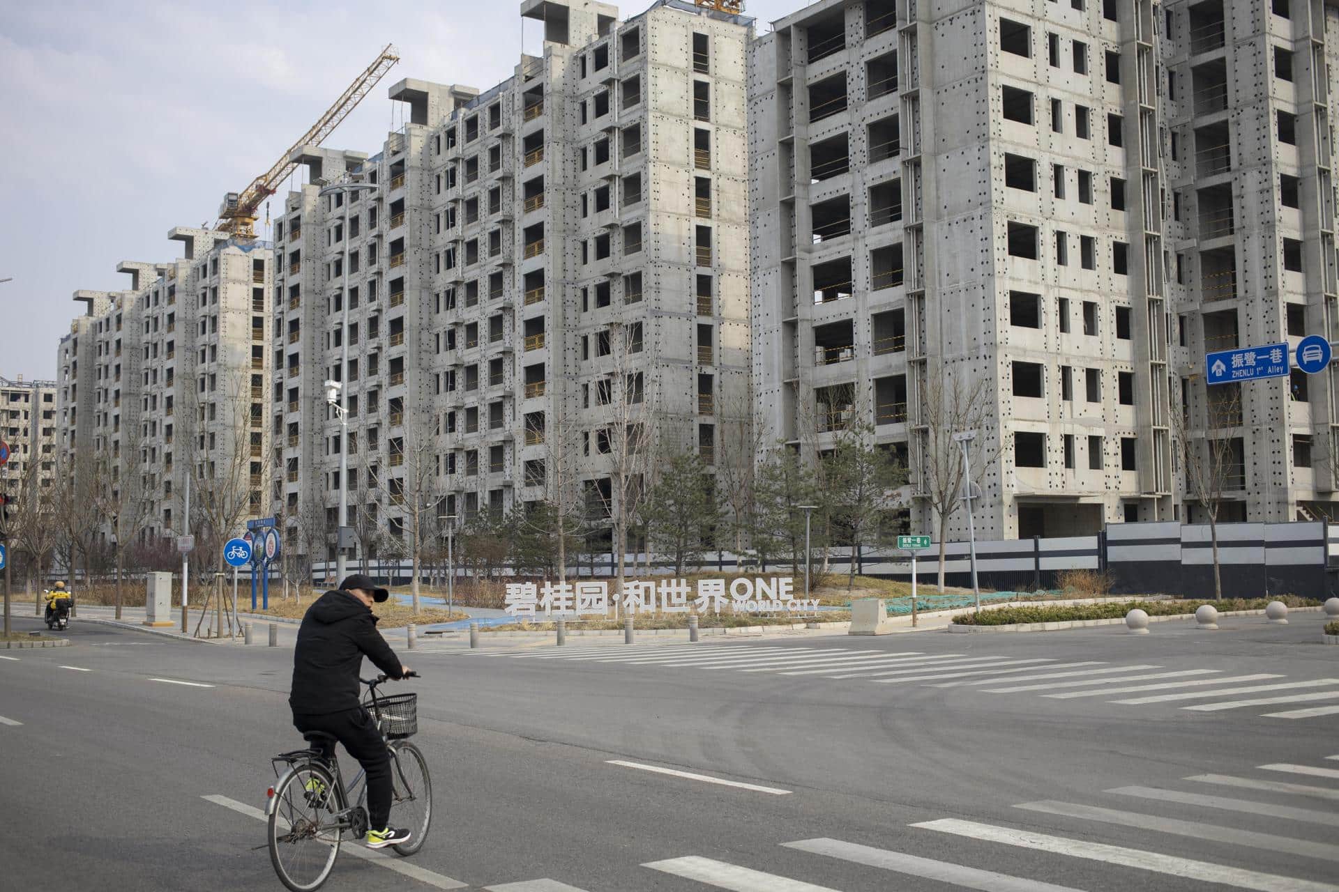 Fotografía de archivo de un hombre en bicicleta junto a un sitio de construcción en Pekín, China. EFE/ANDRÉS MARTÍNEZ CASARES