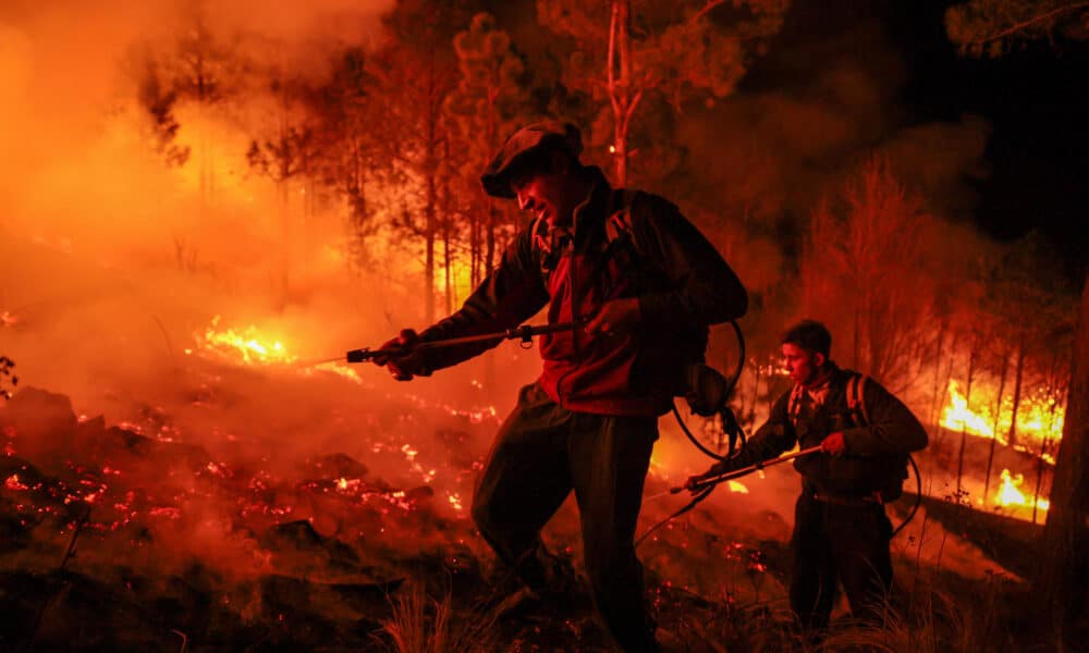 Fotografía de archivo de dos hombres parte de un grupo de bomberos y vecinos autogestionados que combaten un incendio forestal en Intiyaco en las cercanías de Villa Berna, provincia de Córdoba (Argentina). EFE/ STR