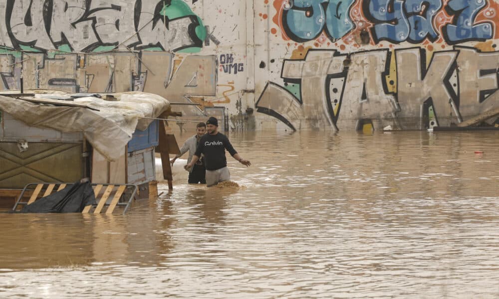 GRAFCVA3847. VALENCIA, 30/10/2024.- Dos personas vadean un terreno de chabolas inundado junto a la V-30 a causa de las lluvias torrenciales de las últimas horas. EFE/Biel Aliño