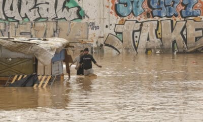 GRAFCVA3847. VALENCIA, 30/10/2024.- Dos personas vadean un terreno de chabolas inundado junto a la V-30 a causa de las lluvias torrenciales de las últimas horas. EFE/Biel Aliño