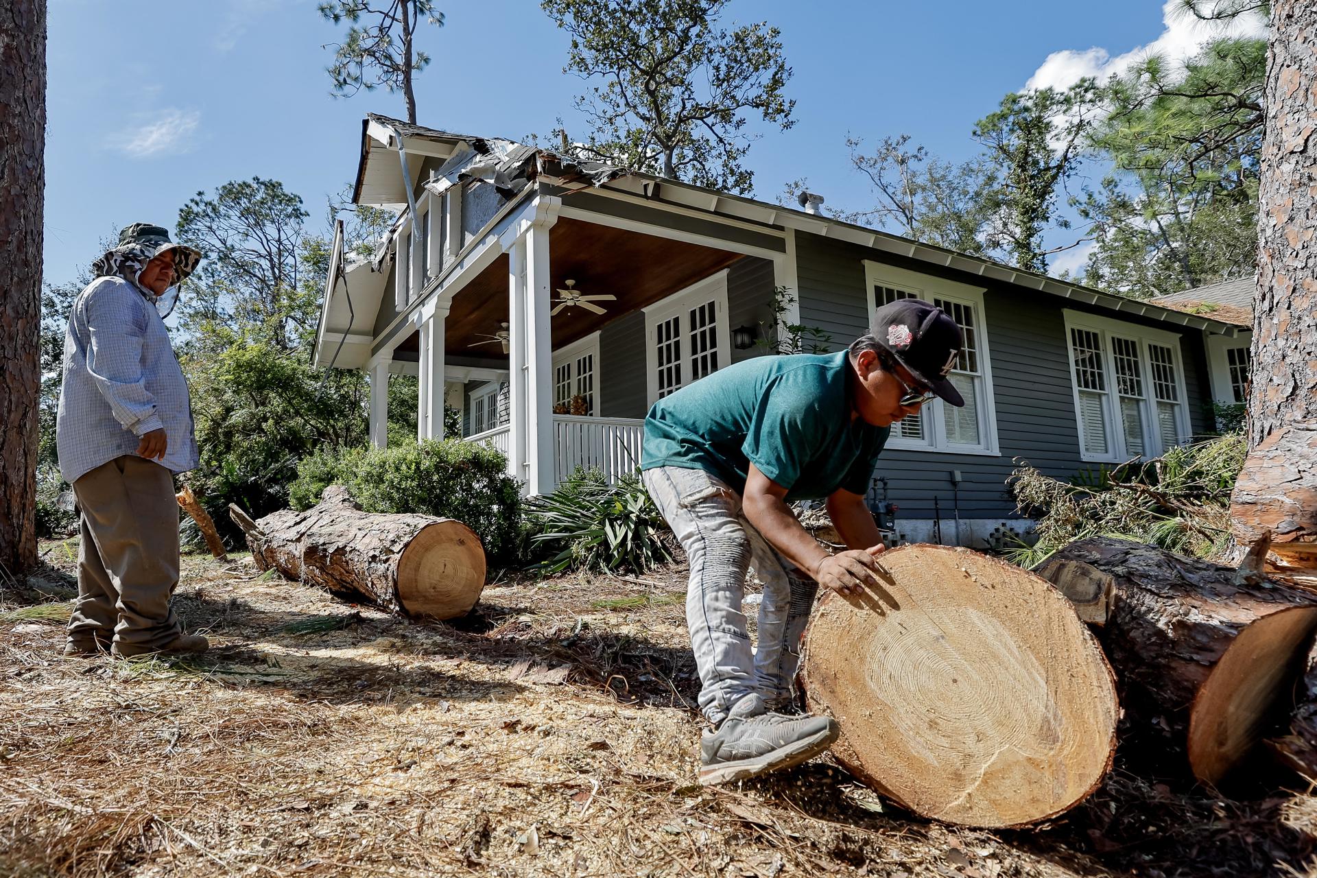 Ángel Sánchez (derecha) y Miguel García (izquierda) cortan un pino caído que dañó una casa después de que el huracán Helene arrasara Valdosta, Georgia, EE. UU., el 30 de septiembre de 2024. EFE/Erik S. Menor