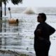 Fotografía de archivo de una mujer frente a una carretera inundada cerca del lago Pontchartrain, en Estados Unidos, mientras se aproxima un huracán EFE/ DAN ANDERSON