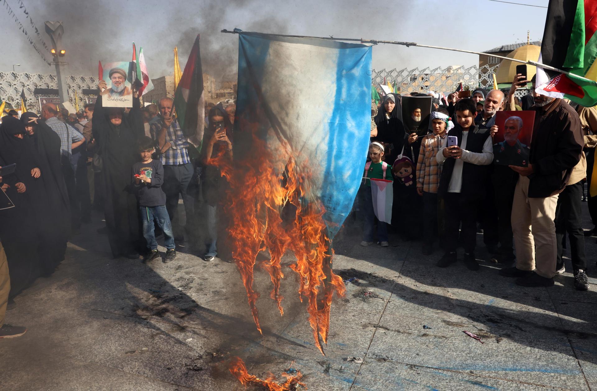 Teherán (EFE).- La gente quema una bandera israelí mientras se reúne para una manifestación contra Israel tras un ataque con misiles llevado a cabo por Irán contra Israel la noche anterior, en la Plaza Imam Hussein en Teherán. EFE/EPA/ABEDIN TAHERKENAREH