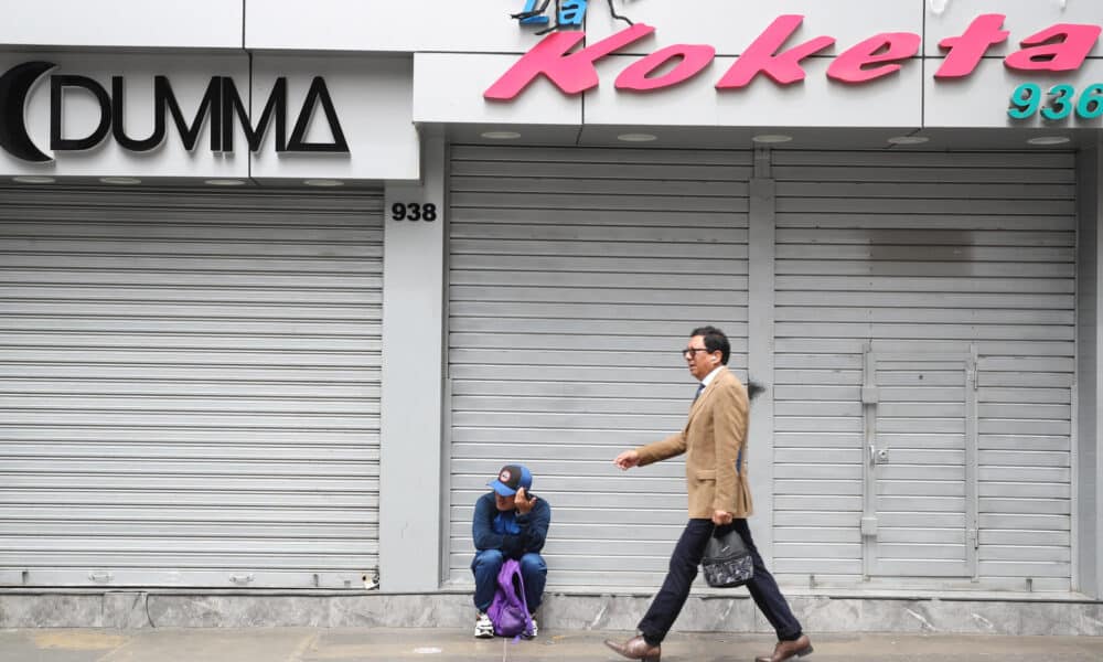 Una persona camina junto a locales comerciales cerrados, durante un paro convocado por gremios de transporte y comercio, este miércoles, en la ciudad de Lima (Perú). EFE/ Paolo Aguilar