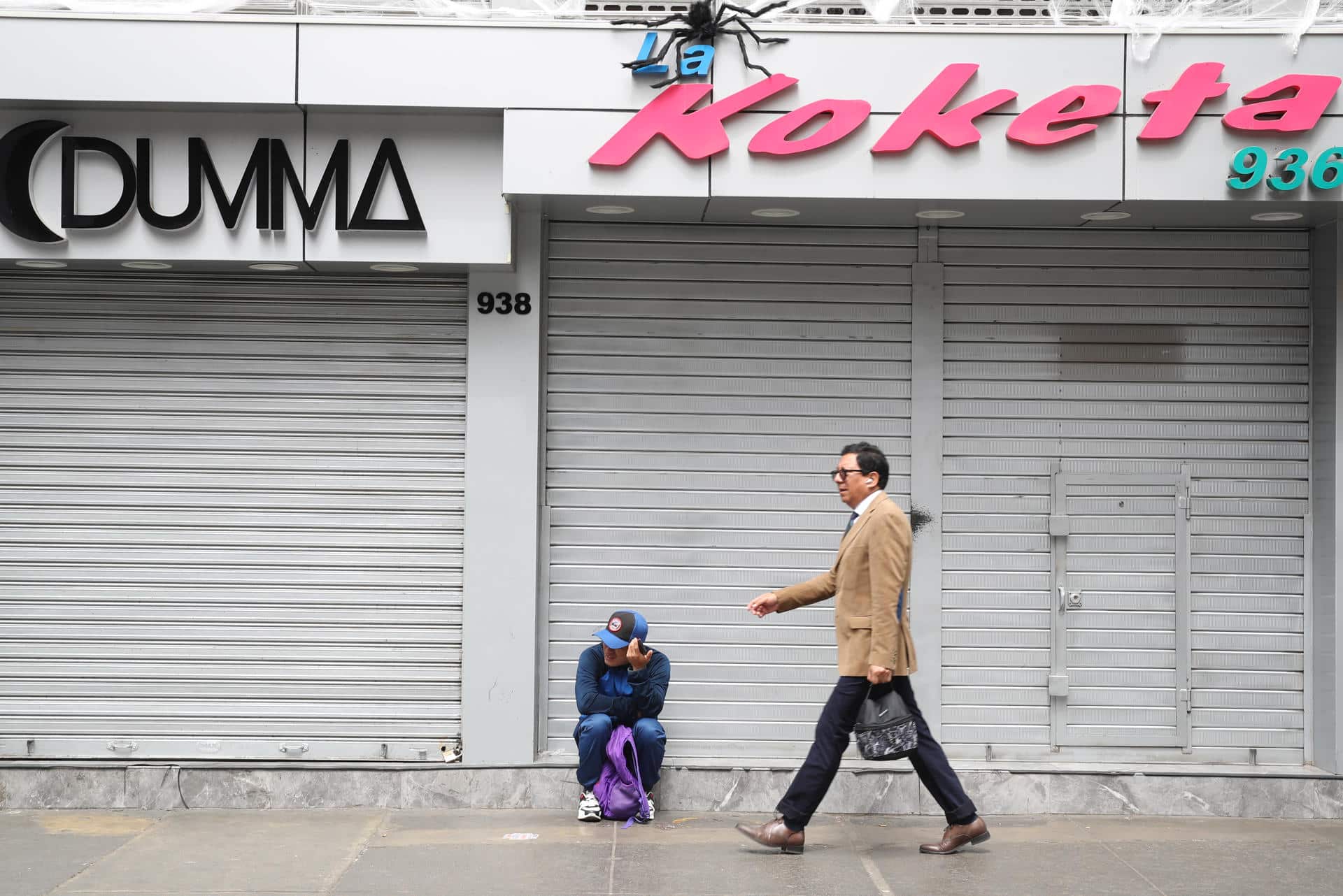 Una persona camina junto a locales comerciales cerrados, durante un paro convocado por gremios de transporte y comercio, este miércoles, en la ciudad de Lima (Perú). EFE/ Paolo Aguilar