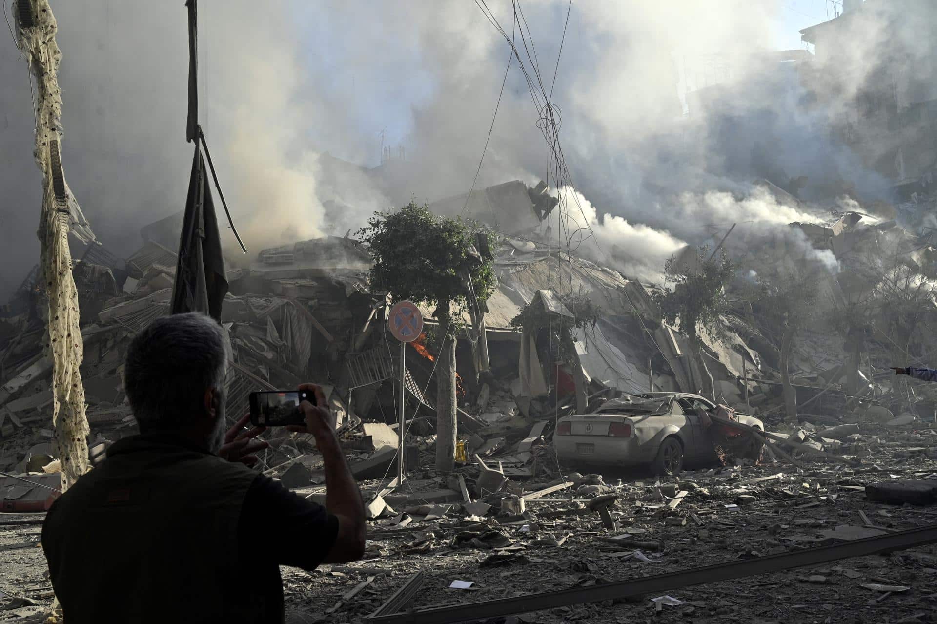 Un hombre fotografía un edificio humeante después de un ataque aéreo israelí sobre el barrio de Dahieh, uno de los bastiones de Hizbulá, en Beirut (El Líbano) estes jueves. EFE/ Wael Hamzeh