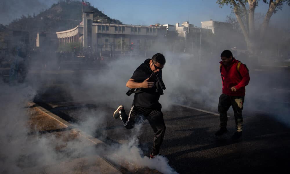 Imagen de archivo de personas que corren entre gases lacrimógenos que utiliza la Policía para dispersar a los manifestantes en la mítica plaza de Santiago de Chile, durante la conmemoración del cuarto aniversario del estallido social. EFE/Ailen Díaz