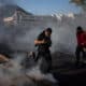 Imagen de archivo de personas que corren entre gases lacrimógenos que utiliza la Policía para dispersar a los manifestantes en la mítica plaza de Santiago de Chile, durante la conmemoración del cuarto aniversario del estallido social. EFE/Ailen Díaz