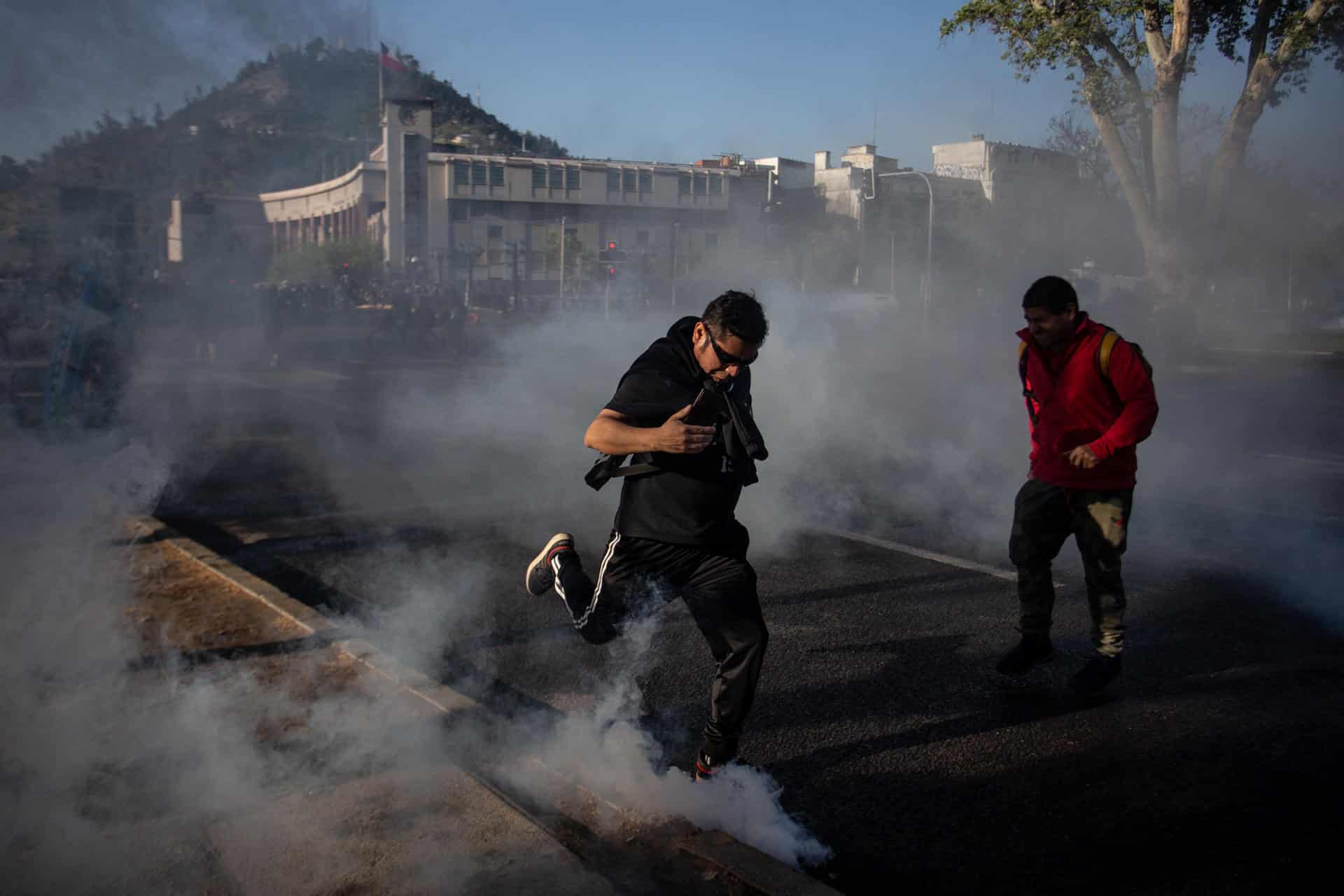 Imagen de archivo de personas que corren entre gases lacrimógenos que utiliza la Policía para dispersar a los manifestantes en la mítica plaza de Santiago de Chile, durante la conmemoración del cuarto aniversario del estallido social. EFE/Ailen Díaz