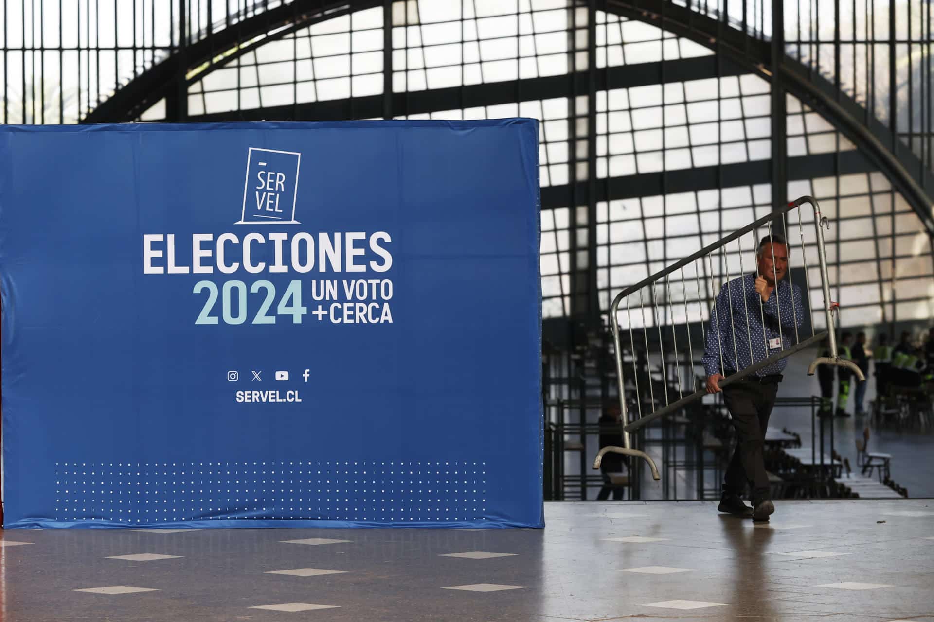 Un hombre trabaja en los preparativos de un centro de votación, este viernes en Santiago (Chile). El Gobierno del presidente progresista Gabriel Boric, golpeado por un escándalo de presunta violación protagonizada por un popular exsubsecretario, medirá su fuerza este fin de semana en unos comicios municipales y regionales considerados un termómetro de la presidenciales de 2025. EFE/ Elvis González