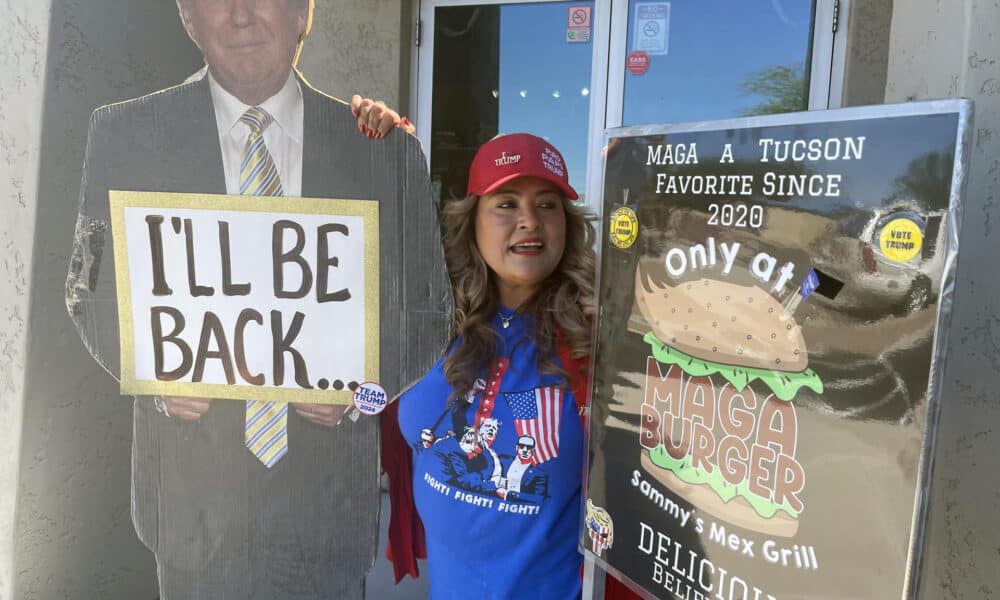 Fotografía del 28 de septiembre de 2024 de la mexicana Betty Rivas, posando junto a los carteles a favor del expresidente republicano Donald Trump, uno con su imagen que dice 'I'll be back' (Volveré) y otro de su hamburguesa 'MAGA Burguer', bautizada con las siglas de la campaña de Trump 'Make America Great Again' (Hacer EEUU grande de nuevo), en la puerta de su restaurante Sammy's Mexican Grill, en Catalina, Arizona (Estados Unidos). EFE/ Ana Milena Varón