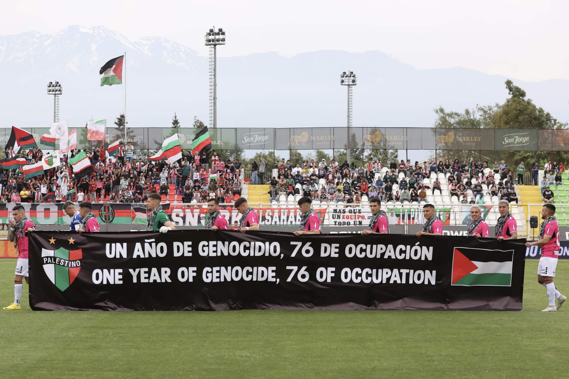 Fotografía cedida por Comunicaciones Club Deportivo Palestino de jugadores de ese equipo sosteniendo una pancarta antes de empezar un partido este domingo, en Santiago de Chile (Chile).. EFE/ Comunicaciones Club Deportivo Palestino /