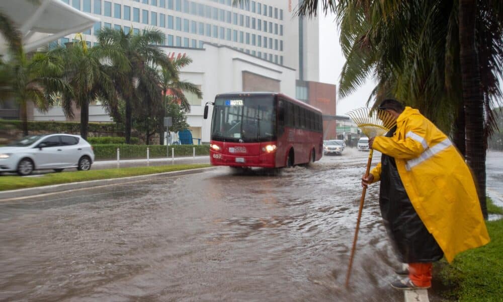 Imagen de archivo de un hombre que destapa un desagüe en una vía inundada debido a las intensas lluvias provocadas en Cancún (México). EFE/Lourdes Cruz