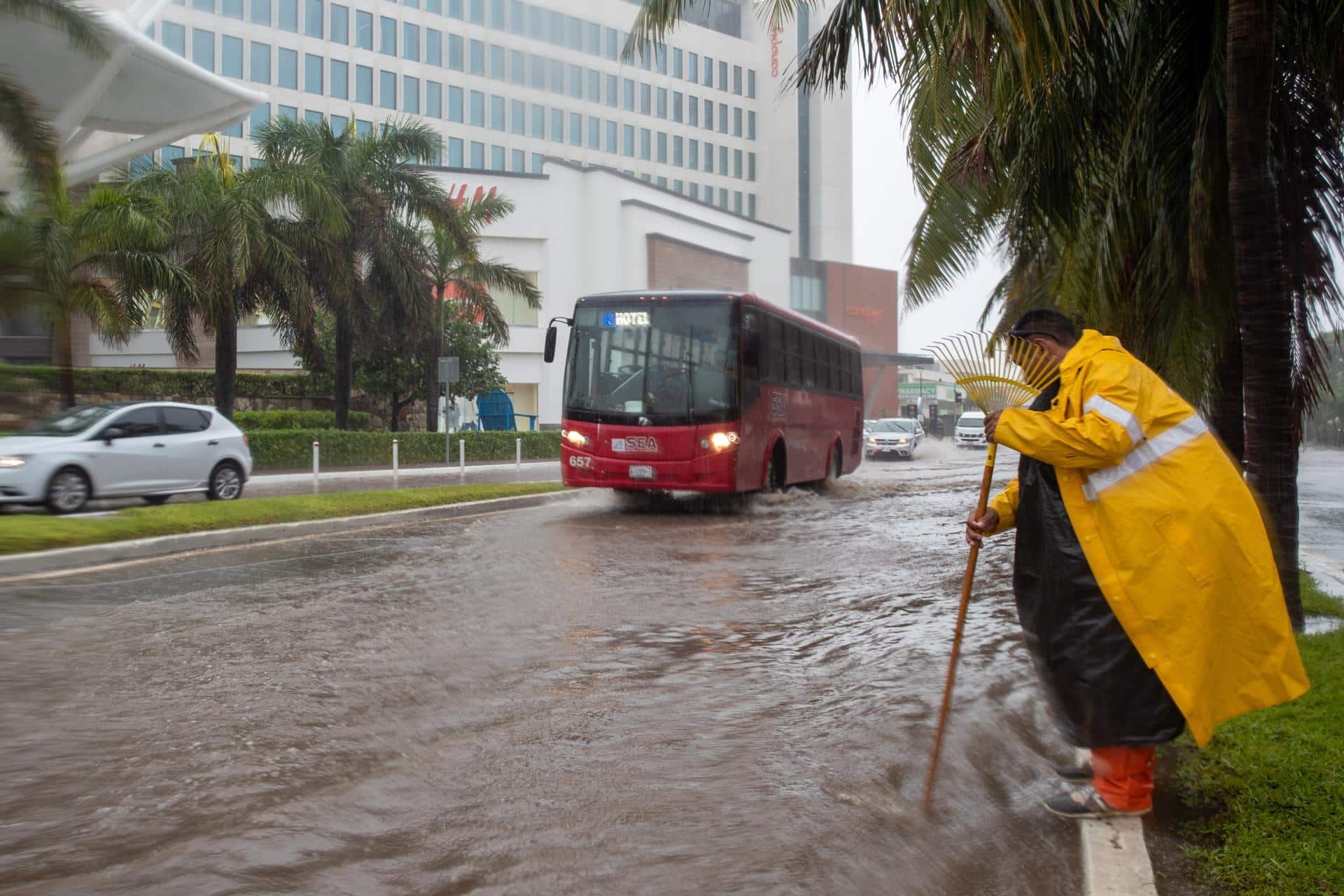 Imagen de archivo de un hombre que destapa un desagüe en una vía inundada debido a las intensas lluvias provocadas en Cancún (México). EFE/Lourdes Cruz