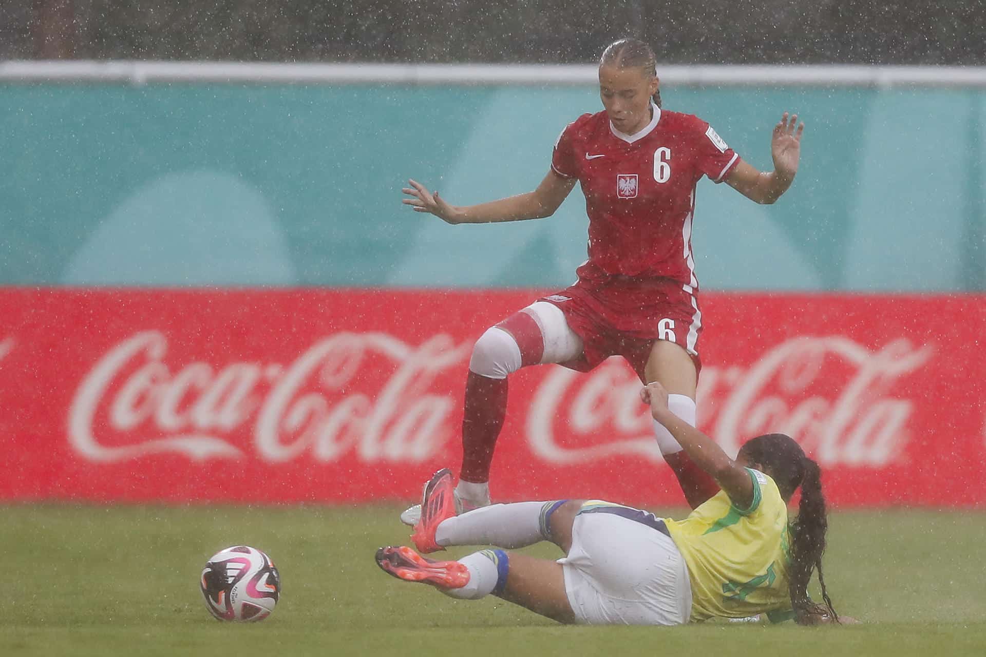 Iga Witkowska (i), de Polonia, disputa un balón con la brasileña Giovanna Waksman en partido del grupo D que se jugó bajo un torrencial aguacero y que dejó eliminada a la Canarinha en Santiago de los Caballeros. EFE/ Diana Sánchez