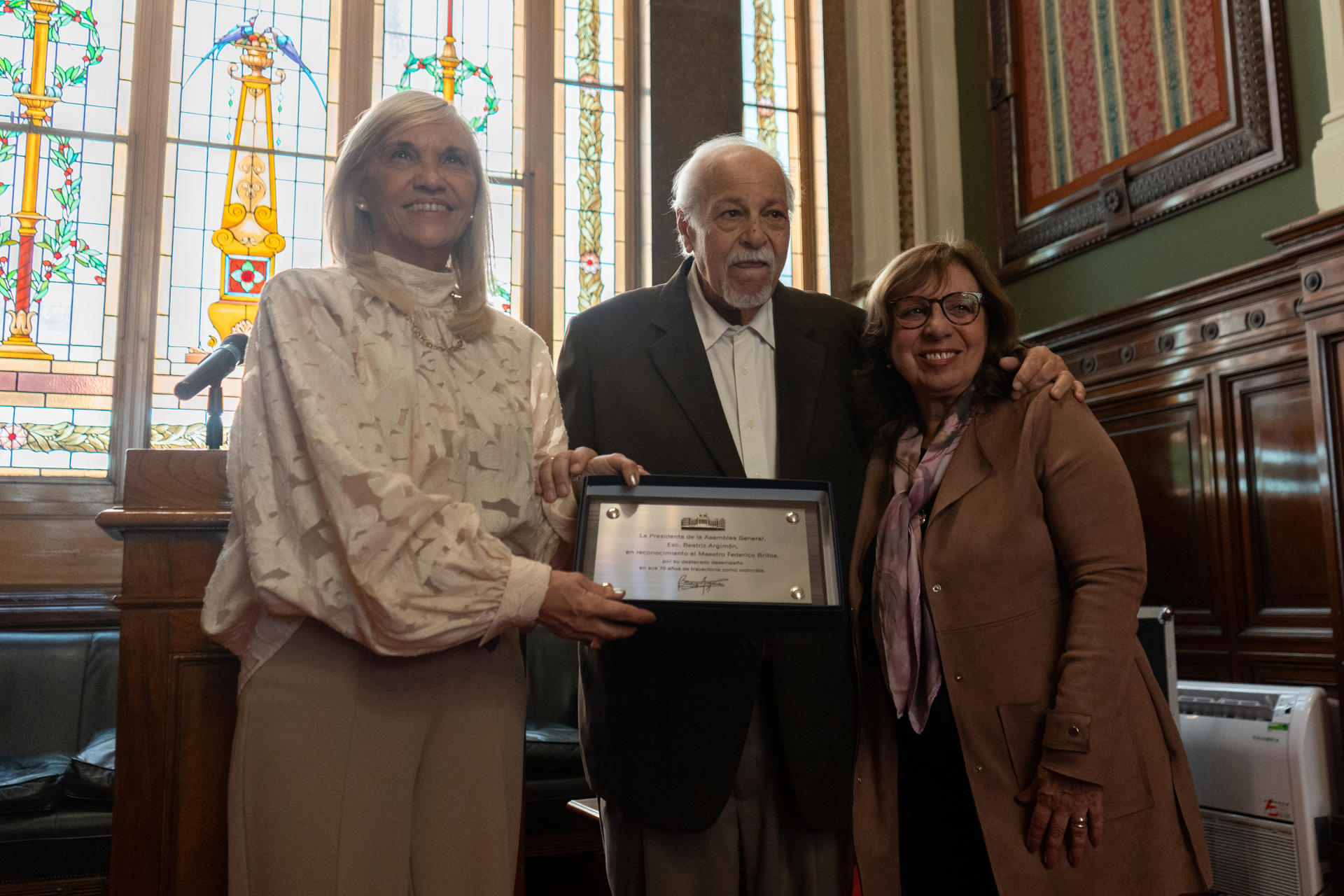 El violinista uruguayo Federico Britos, posa junto a la vicepresidenta de Uruguay, Beatriz Argimón (i), y a la presidenta de la Cámara de Diputados, Ana Olivera, durante un reconocimiento por parte del Parlamento este miércoles en Montevideo (Uruguay). EFE/ Sofía Torres