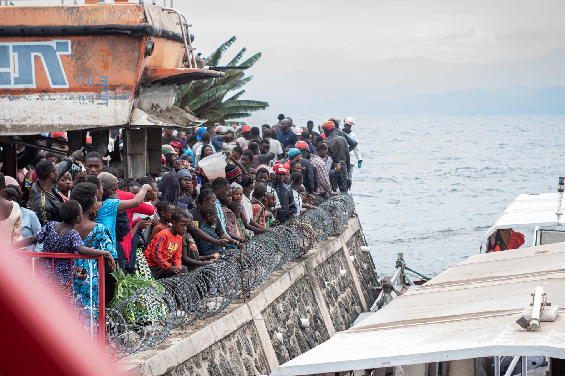 Familiares de las víctimas del naufragio de un barco en el lago Kivu esperan noticias en el muelle. EFE/EPA/MARIE JEANNE MUNYERENKANA