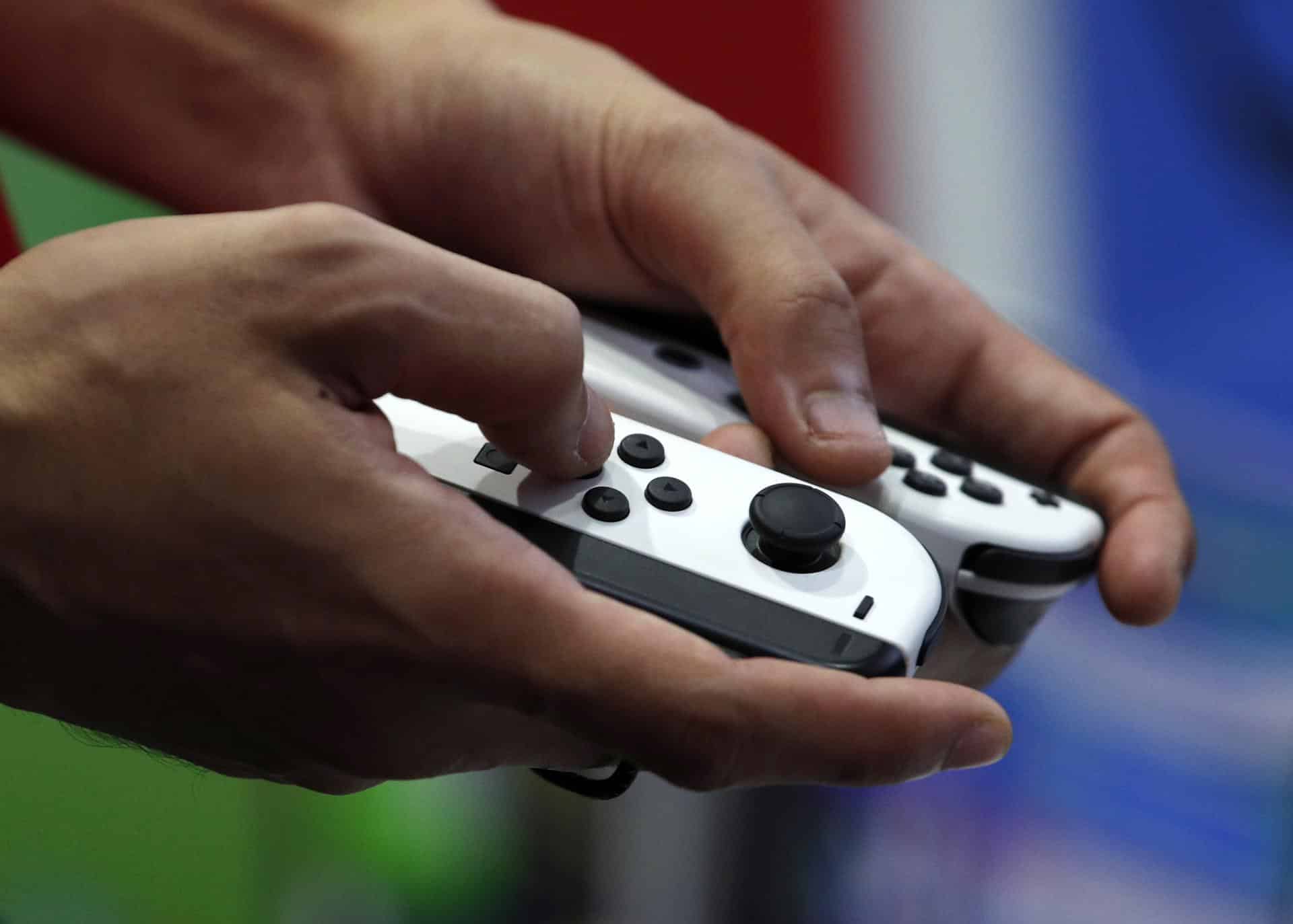 Una persona sujeta con las manos unos controladores Nintendo Switch. EFE/EPA/RUNGROJ YONGRIT