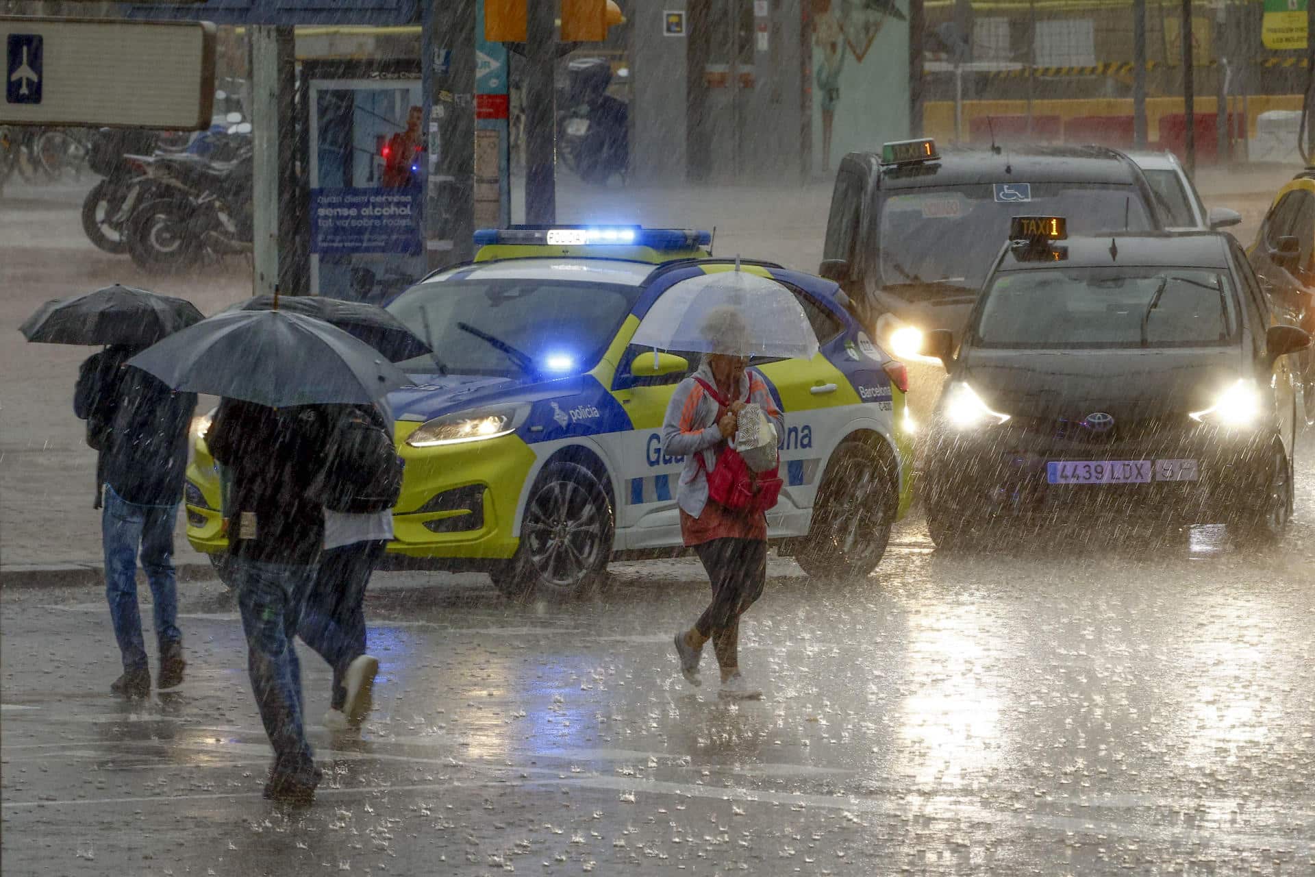 Varias personas se protegen de la lluvia en la Plaza de Espanya de Barcelona este lunes cuando las comarcas de del Garraf y del Barcelonès, en Barcelona, están en aviso rojo de la Agencia Estatal de Meteorología (Aemet), y la Generalitat ha enviado una alerta a los teléfonos móviles por la llegada de lluvias continuadas y torrenciales. EFE/Quique García