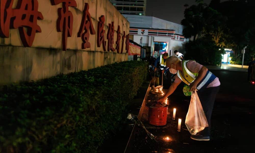 Trabajadores retiran flores y velas dejadas por los dolientes por las víctimas de un accidente automovilístico, en la entrada del centro deportivo de Zhuhai en Zhuhai, China. EFE/EPA/ALEX PLAVEVSKI