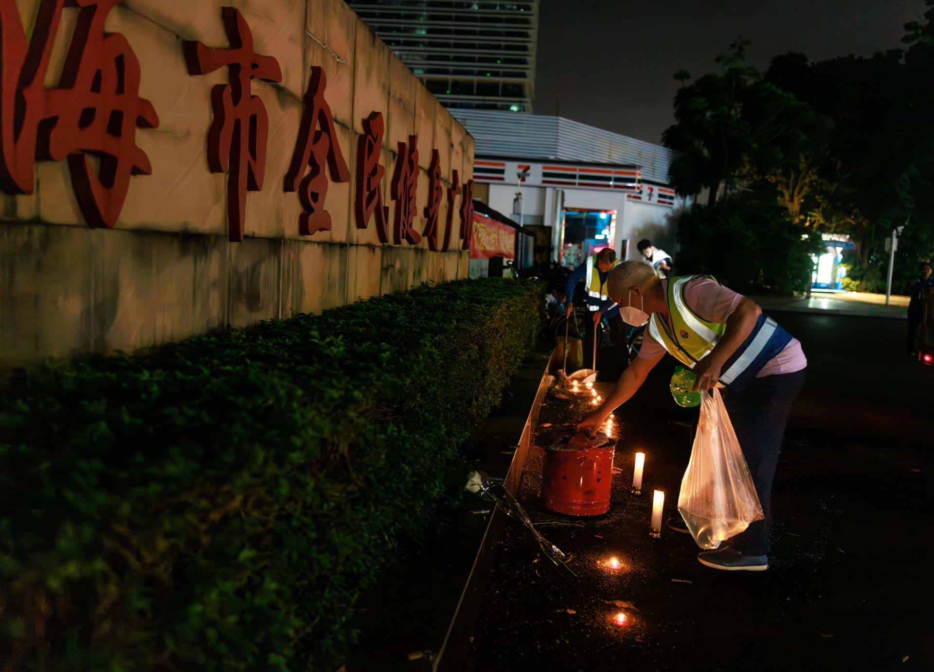 Trabajadores retiran flores y velas dejadas por los dolientes por las víctimas de un accidente automovilístico, en la entrada del centro deportivo de Zhuhai en Zhuhai, China. EFE/EPA/ALEX PLAVEVSKI