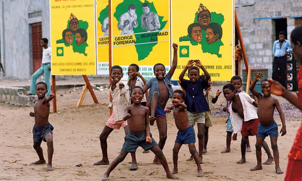 Niños en Kinsasa, el antiguo Zaire, actual capital de la República Democrática del Congo, delante de unos carteles de la pelea entre Muhammad Ali y George Foreman de 1974. EFE/Cedida por Taschen