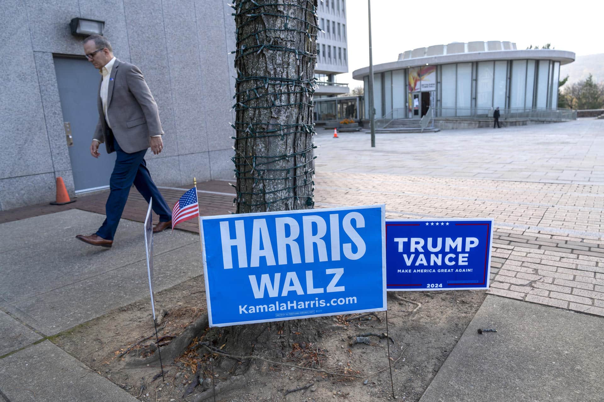 Un hombre camina frente a unos carteles de los candidatos presidenciales, los demócratas Harris y Walz y los republicanos Trump y Vance, en un centro de votación. EFE/ Ángel Colmenares