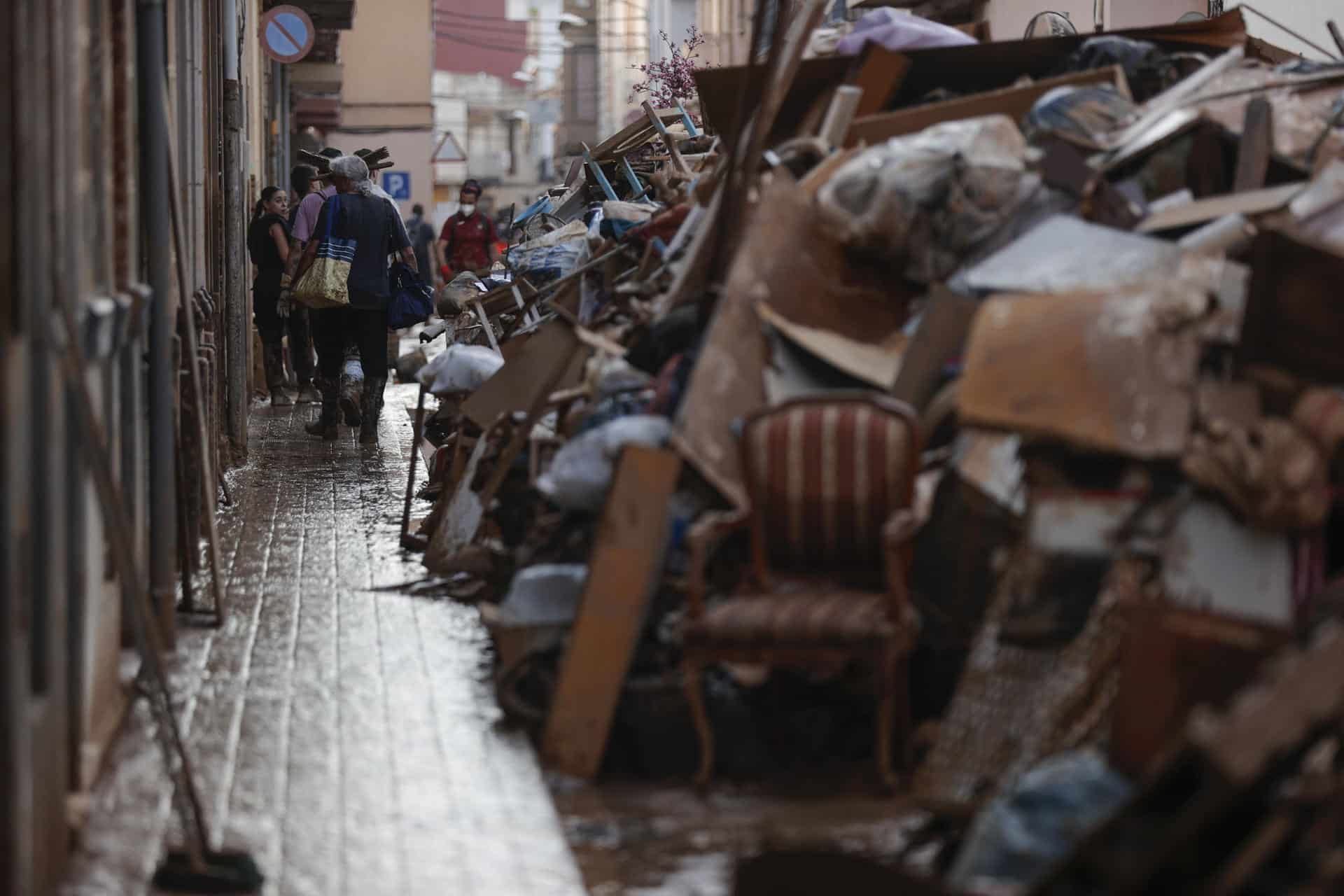 Voluntarios y vecinos trabajan para despejar una calle de Paiporta (Valencia), este martes. Una semana después del paso de la dana, varios de los pueblos más afectados siguen "en shock" y con grandes necesidades, más allá de comida o productos de limpieza y desescombro, a pesar de la ayuda de los miles de voluntarios y el aumento de efectivos de la UME, ejército, bomberos y policías. EFE/ Manuel Bruque