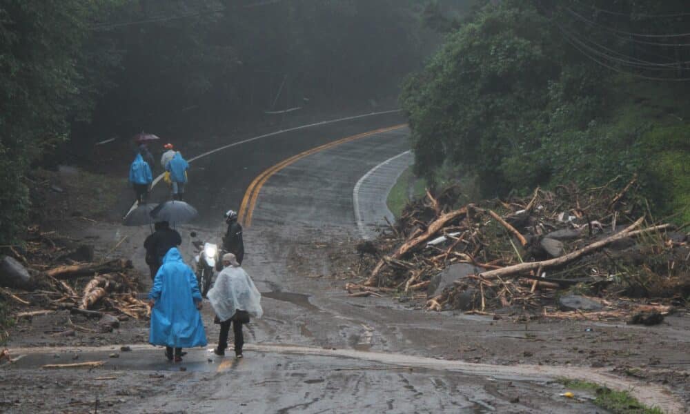 Fotografía de archivo en donde se ven habitantes que caminan por una zona afectada tras las fuertes lluvias. EFE/ Marcelino Rosario