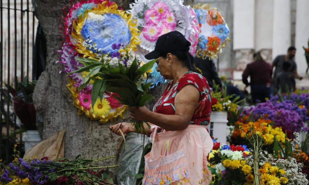 Una mujer vende flores afuera del Cementerio General, en el marco de Día de Muertos, este sábado de la ciudad de Comayagüela (Honduras). EFE/Gustavo Amador