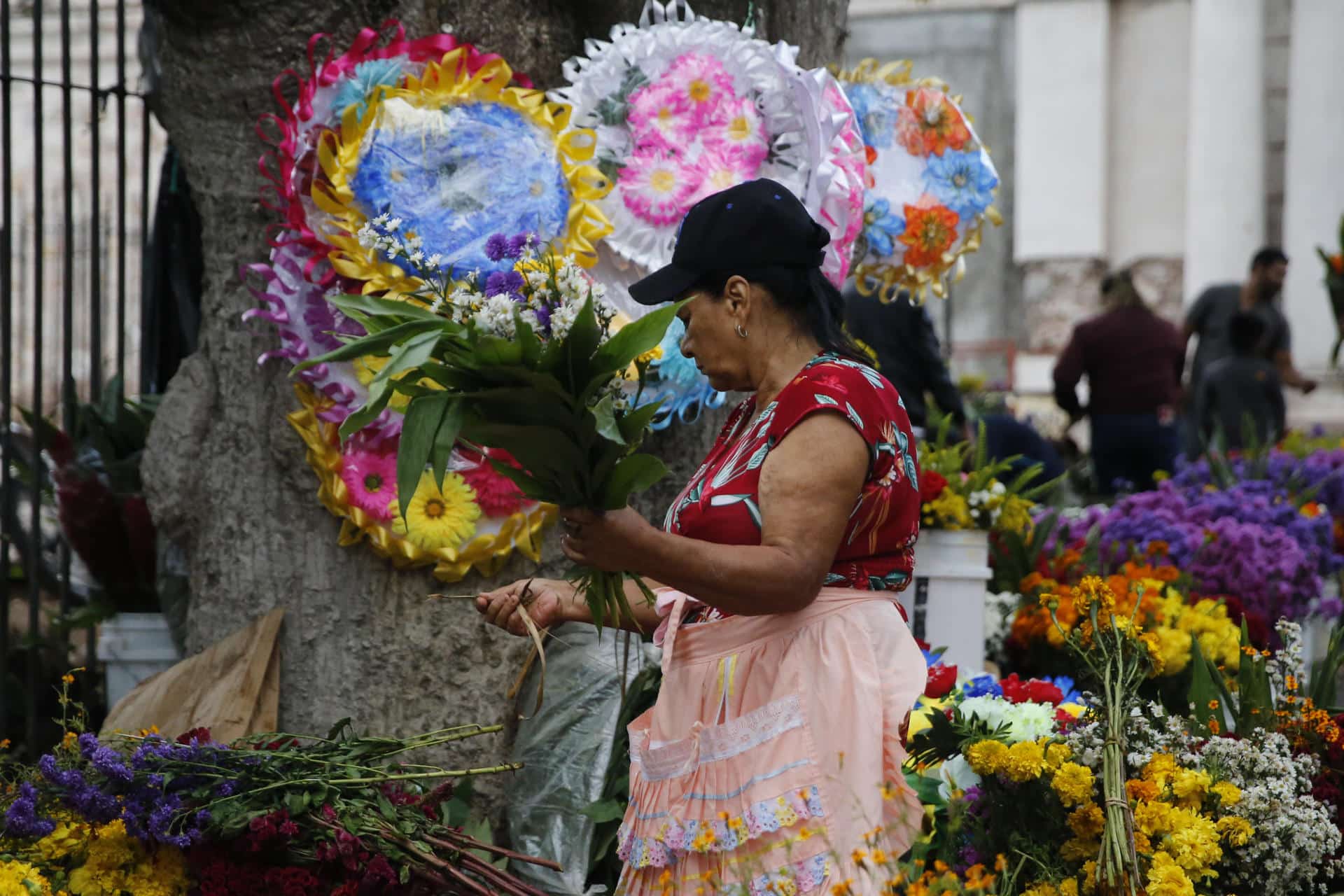 Una mujer vende flores afuera del Cementerio General, en el marco de Día de Muertos, este sábado de la ciudad de Comayagüela (Honduras). EFE/Gustavo Amador