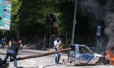 Personas sostienen un tronco en una vía este martes, en una calle de Puerto Príncipe (Haití). EFE/ Johnson Sabin