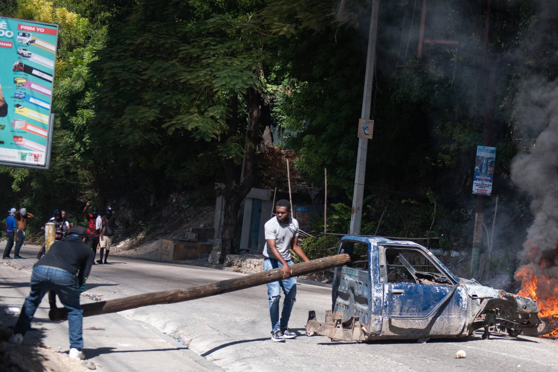 Personas sostienen un tronco en una vía este martes, en una calle de Puerto Príncipe (Haití). EFE/ Johnson Sabin