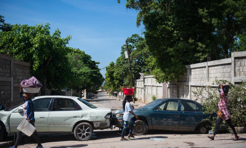 Personas caminan frente a carros abandonados este 13 de noviembre 2024, en Puerto Principe (Haití). EFE/ Johnson Sabin