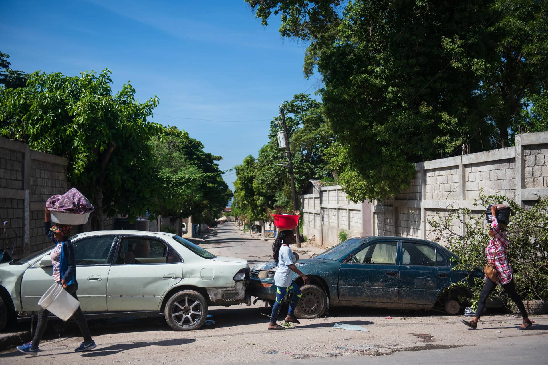 Personas caminan frente a carros abandonados este 13 de noviembre 2024, en Puerto Principe (Haití). EFE/ Johnson Sabin