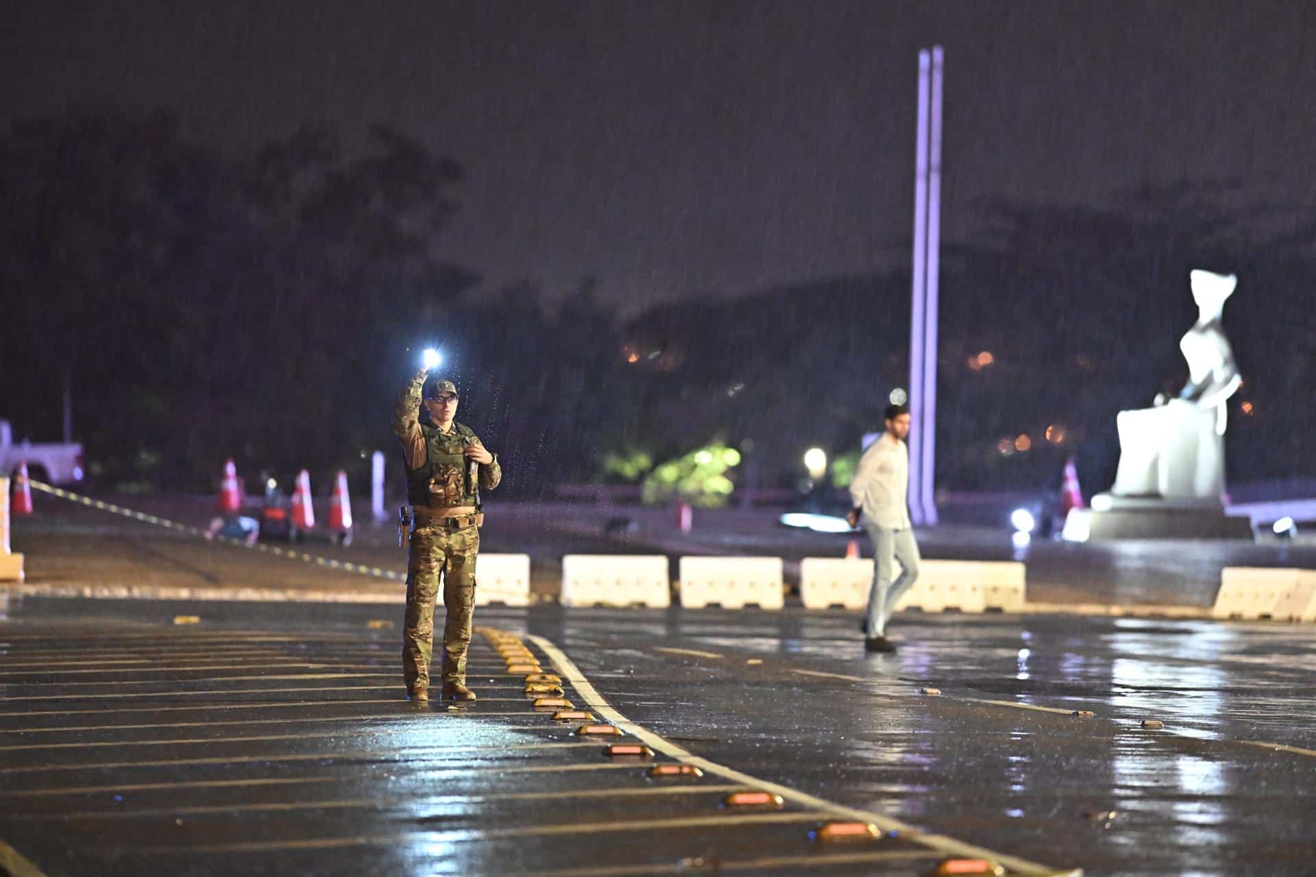 Un miembro de la Policía Militar custodia el lugar de una explosión en la Plaza de los Tres Poderes este miércoles, en Brasilia (Brasil). Las explosiones de dos artefactos en Brasilia detonados frente a la sede del Tribunal Supremo y cerca de la Cámara de los Diputados fueron un ataque suicida, según informaron fuentes de la Policía. EFE/ Andre Borges