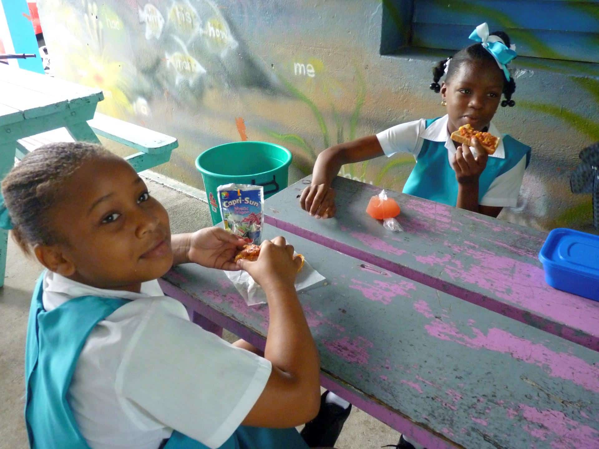 Fotografía de archivo en donde se ven dos niñas mientras toman su refrigerio en una escuela a las afueras de Castries, capital de la isla caribeña de Santa Lucía. EFE/Belén Delgado