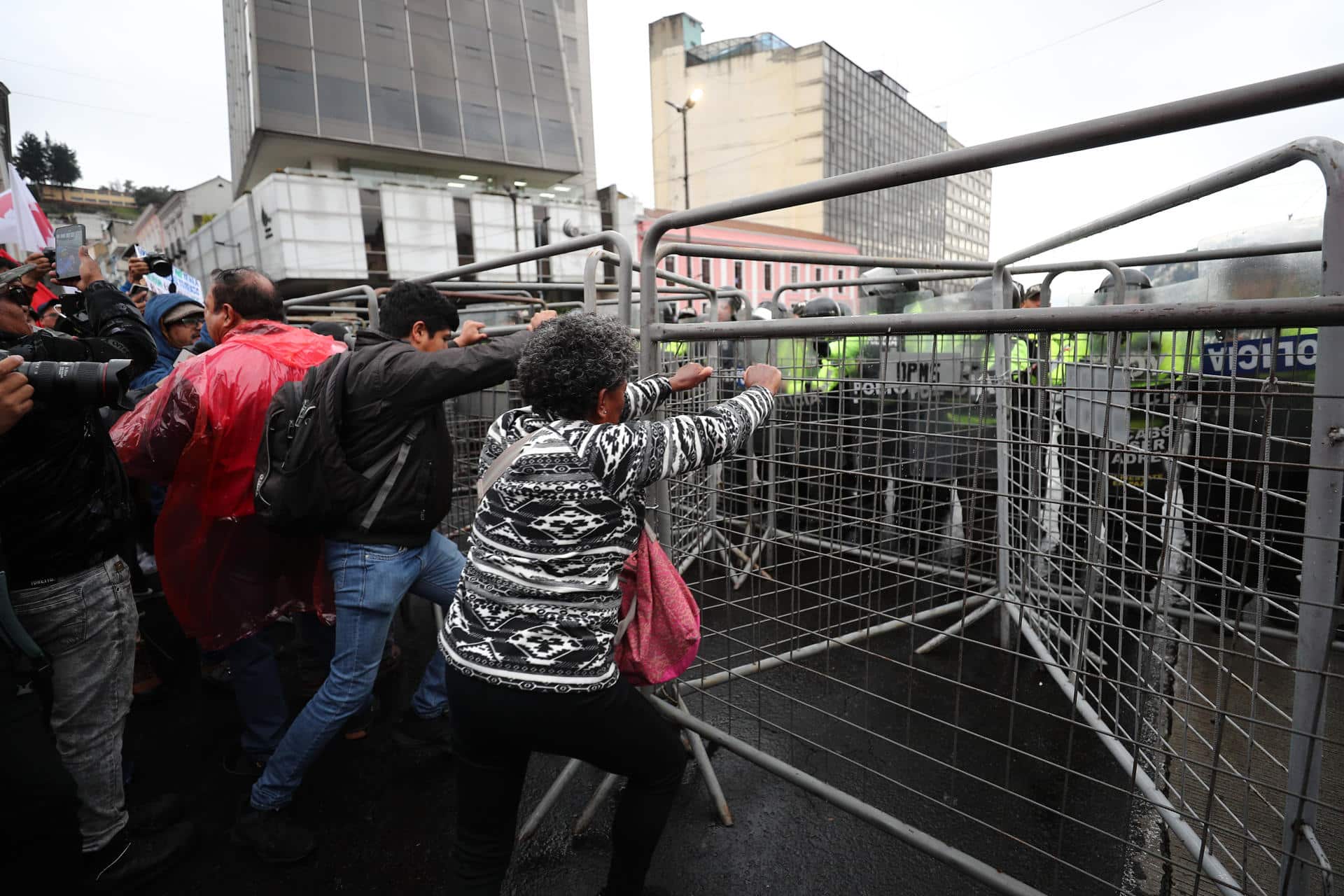 Manifestantes intentan mover rejas que impiden el paso al Centro Histórico este jueves, en Quito (Ecuador). EFE/ José Jácome