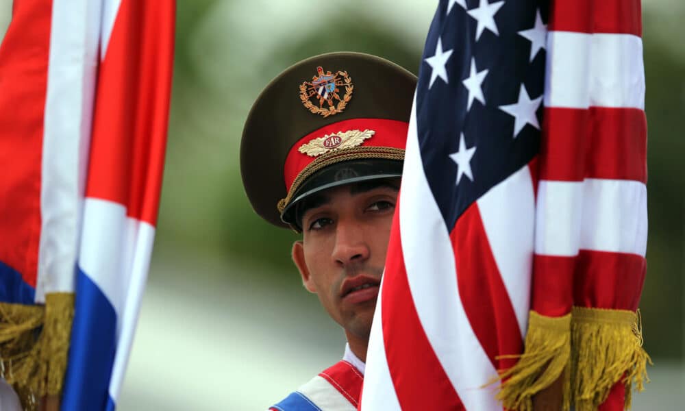 Fotografía de archivo fechada el 21 de marzo de 2016 que muestra un soldado cubano sosteniendo banderas de Cuba y Estados Unidos momentos antes de la llegada del presidente de Estados Unidos Barack Obama, a La Habana (Cuba). EFE. EFE/Alejandro Ernesto