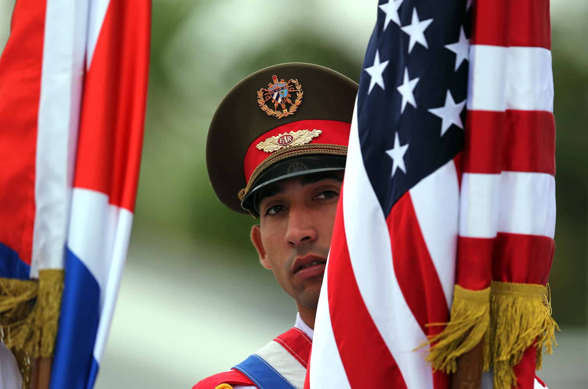 Fotografía de archivo fechada el 21 de marzo de 2016 que muestra un soldado cubano sosteniendo banderas de Cuba y Estados Unidos momentos antes de la llegada del presidente de Estados Unidos Barack Obama, a La Habana (Cuba). EFE. EFE/Alejandro Ernesto