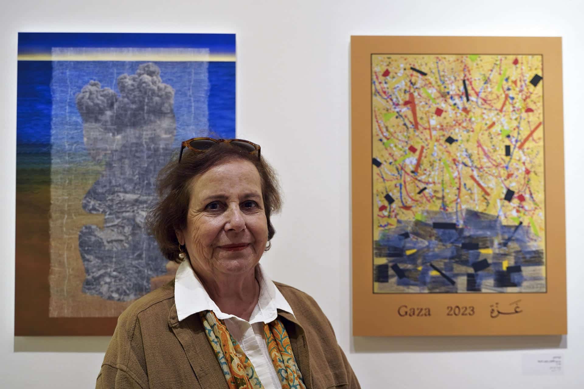 La artista palestina Vera Tamari posa junto a su obra en la exposición Pósteres de Gaza, inaugurada el 3 de noviembre de 2024 en el centro cultural Khalil Sakakini de Ramala (Cisjordania). EFE/ Alejandro Ernesto