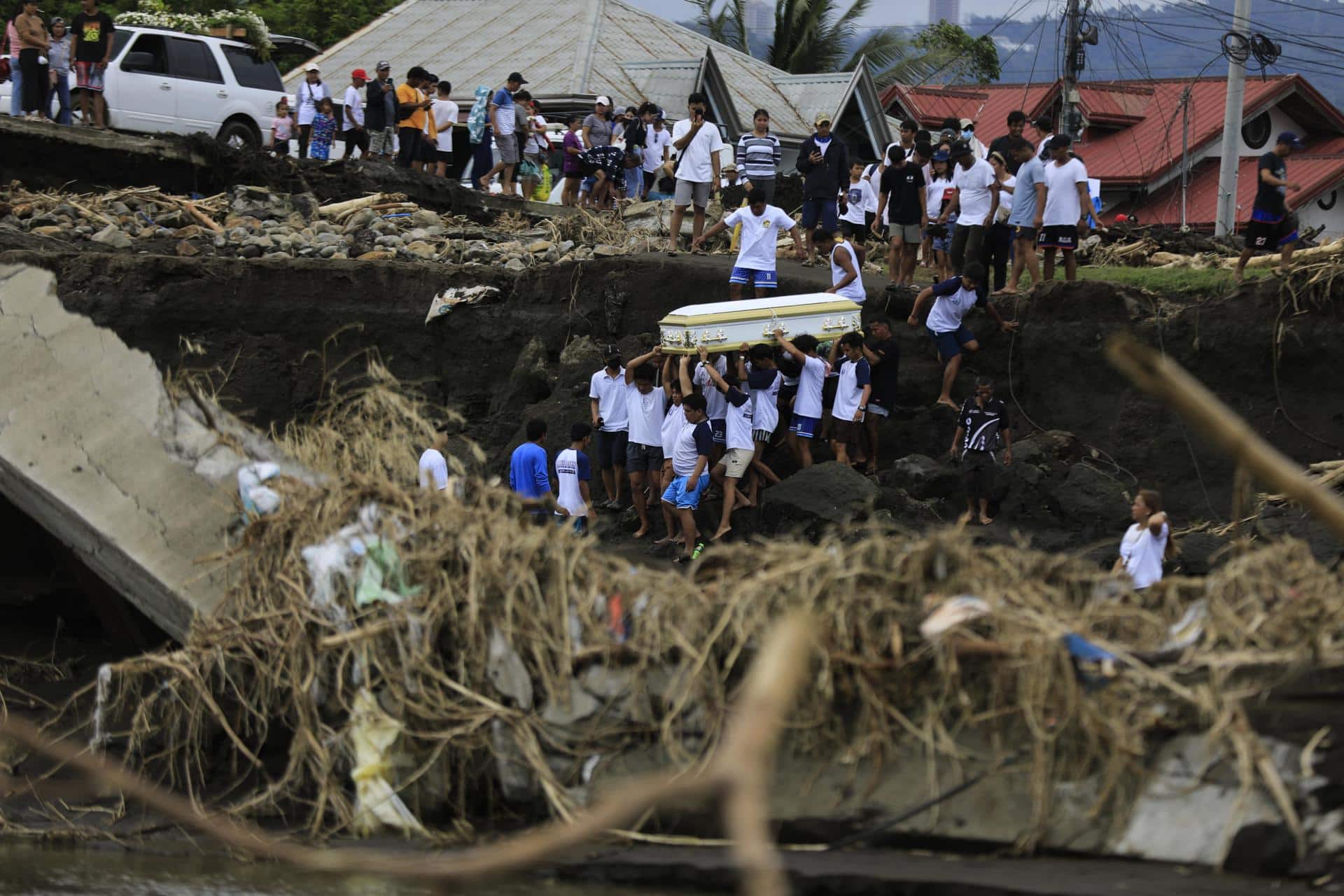 Unos vecinos llevan un ataúd el pasado miércoles en la provincia filipina de Batangas, en el norte del país, tras el paso de la tormenta tropical Trami, que causó 139 muertos y decenas de heridos. EFE/EPA/FRANCIS R. MALASIG