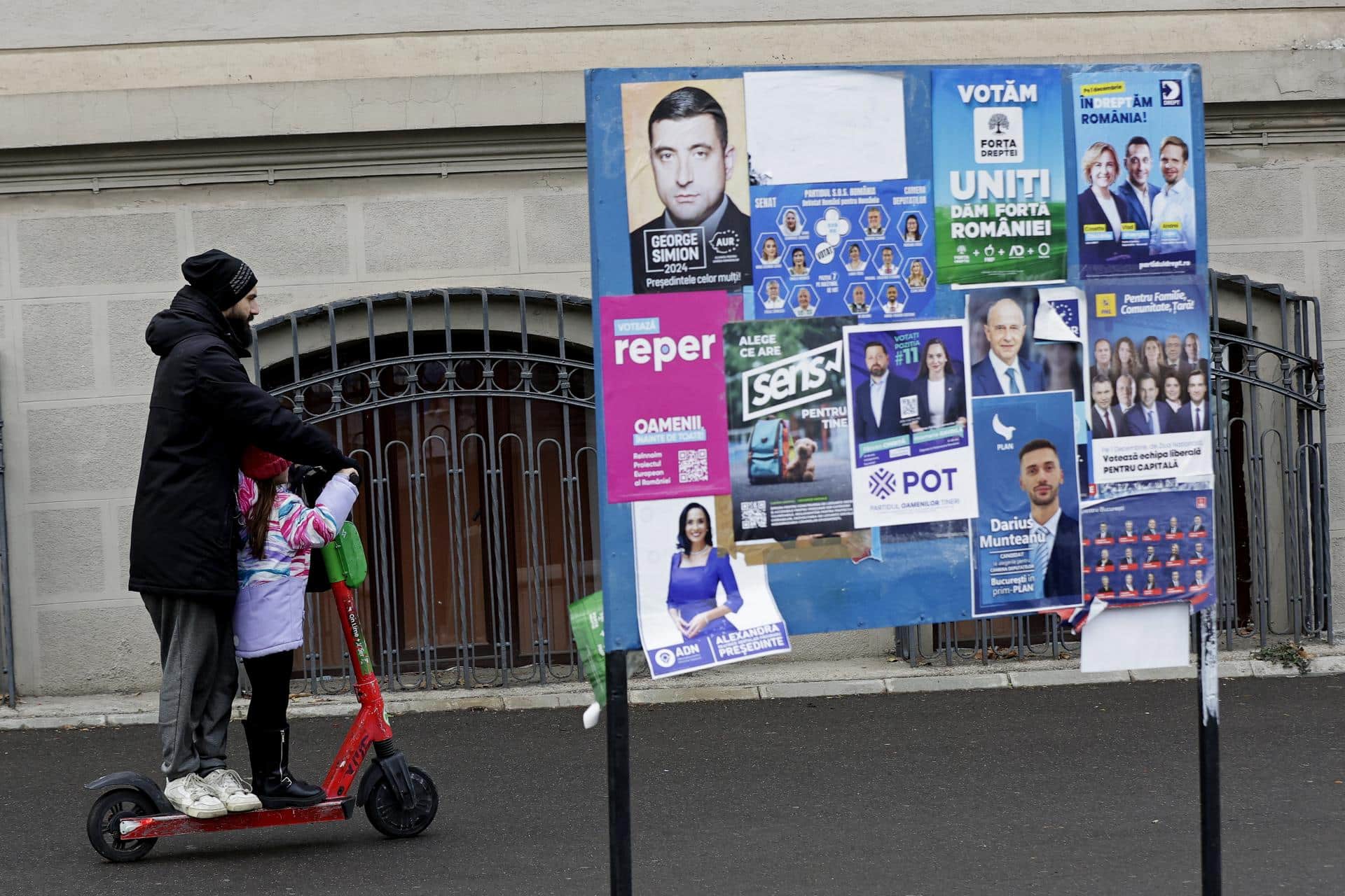 Un padre y una hija pasan por delante de unos carteles electorales en Bucarest. EFE/EPA/ROBERT GHEMENT