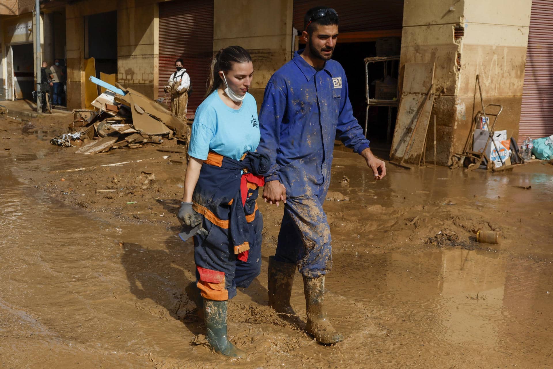 Una pareja camina este sábado por una calle en la localidad valenciana de Paiporta, que afronta el fin de semana con el reto de avanzar en la recuperación de la zona cero de la dana que asoló Valencia hace once días y de encontrar más personas desaparecidas. EFE/ Jorge Zapata