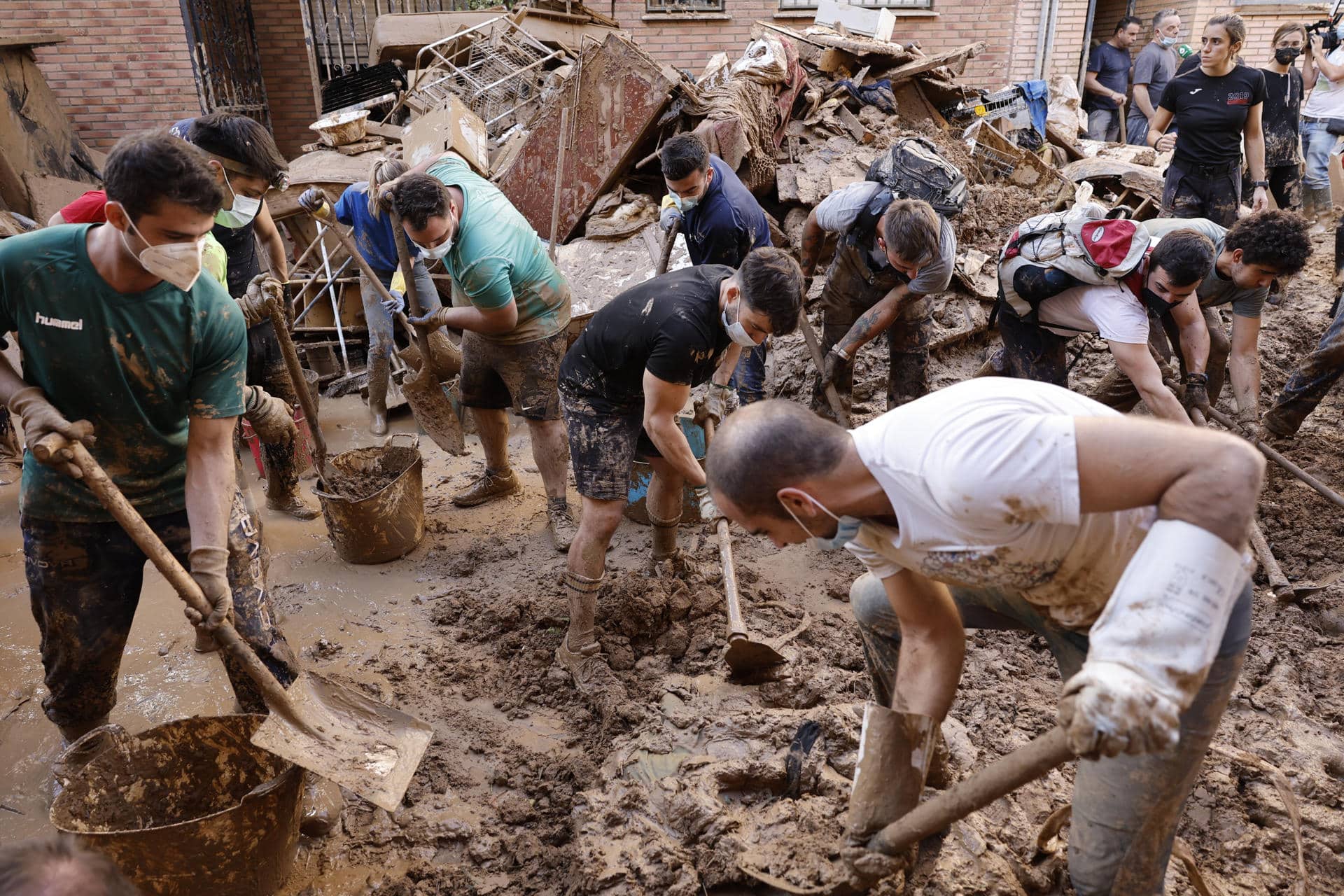 Varias personas retiran el lodo acumulado en una calle de la localidad valenciana de Paiporta, este sábado. Por tercer día consecutivo una marea de voluntarios ha llegado este sábado a barrios del sur de la ciudad de València y a los pueblos de la comarca vecina de l’Horta Sud asolados por la dana para luchar contra un fango, donde grupos especializados de los equipos de intervención buscan cadáveres en garajes o fosos aún anegados.EFE/ Biel Alino