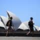 Dos personas pasan este martes delante de la Casa de la Ópera en Sídney en medio de una ola de claro. EFE/EPA/BIANCA DE MARCHI AUSTRALIA AND NEW ZEALAND OUT